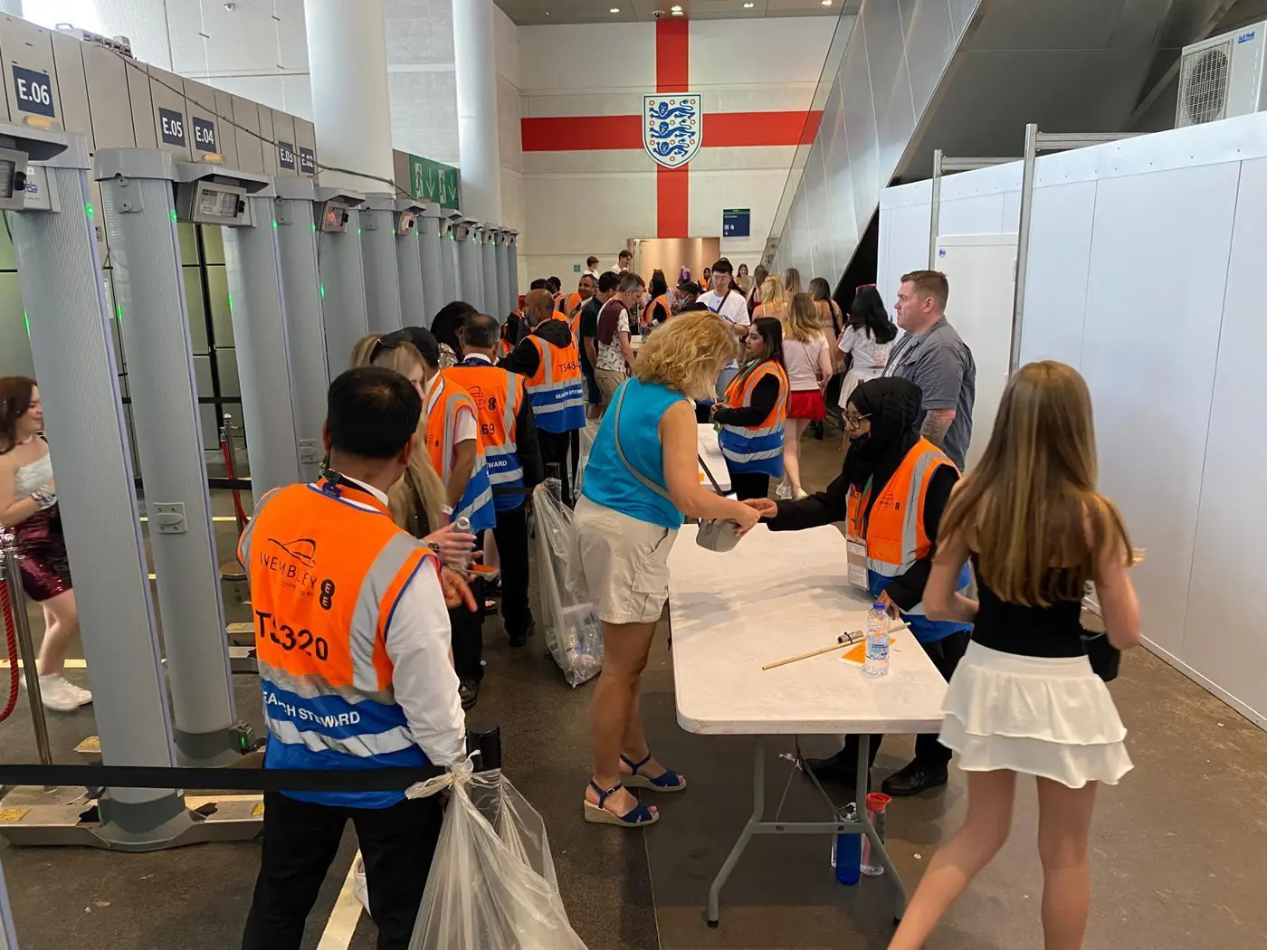 Search stewards processing a queue at stadium security archways