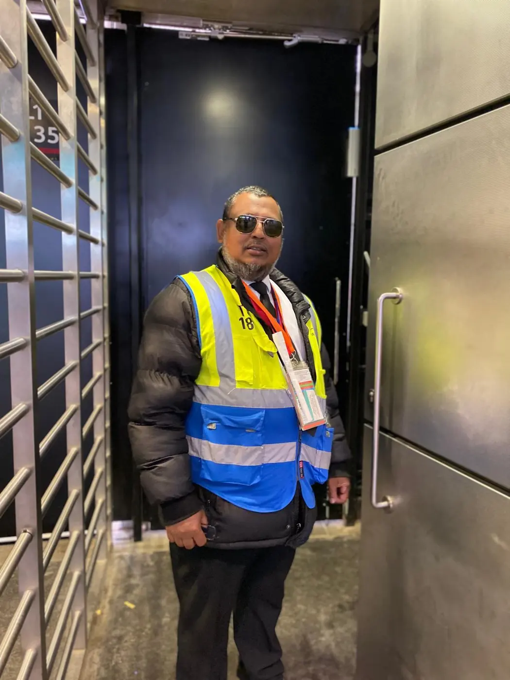 Security officer in a hi-vis jacket at a gated doorway