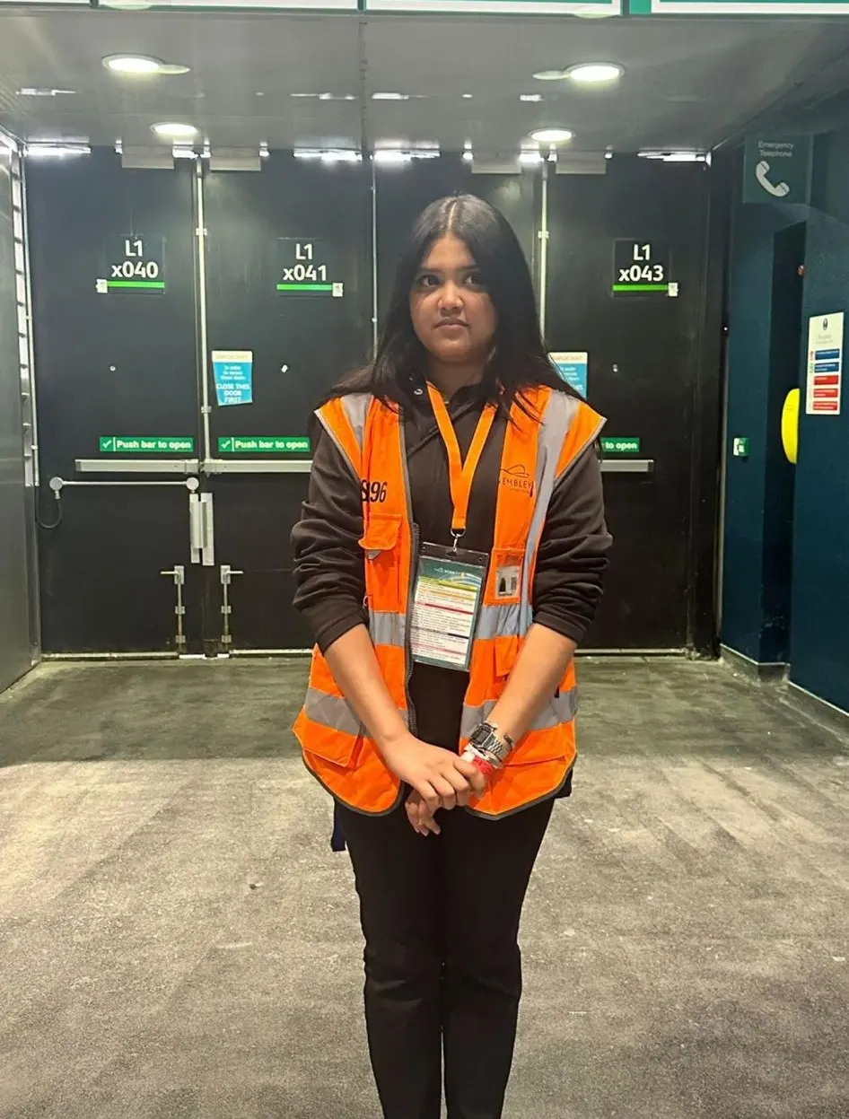 Steward in orange hi-vis with a lanyard in front of venue doors