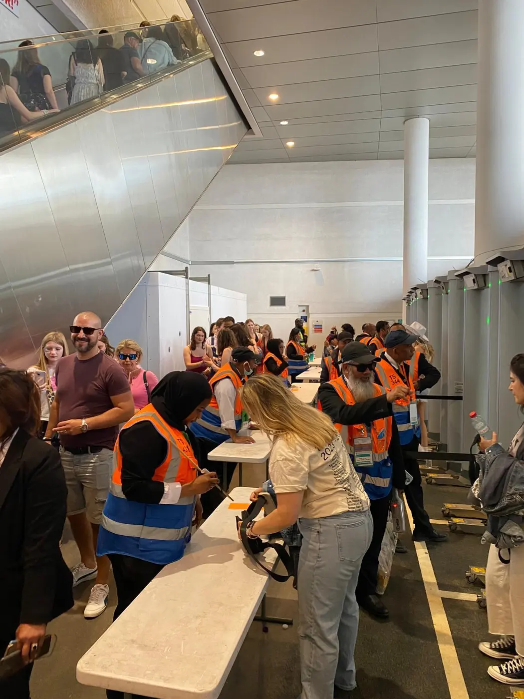 Queue of guests being searched in a busy stadium concourse