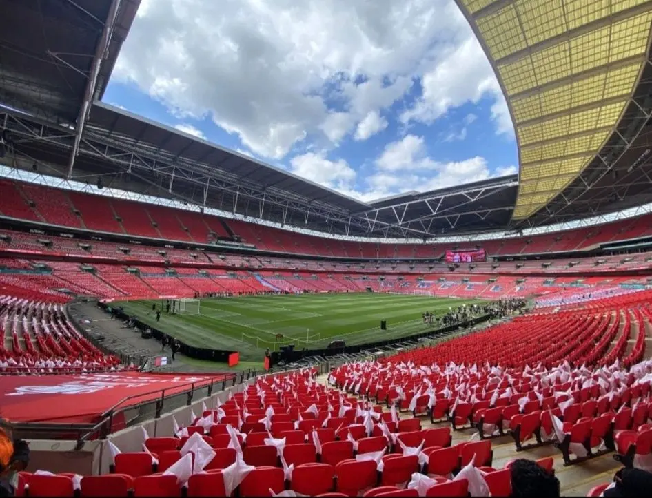 Empty stadium bowl with red seating under a partly cloudy sky